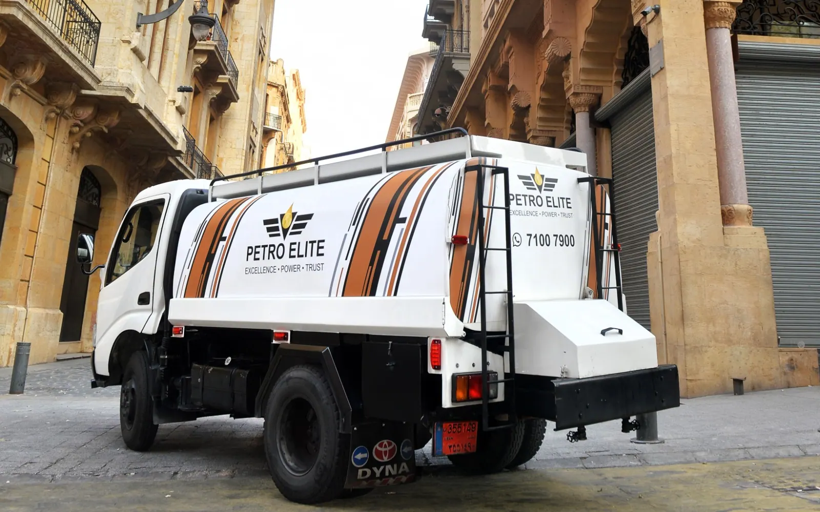 A Petro Elite tanker truck driving through the historic stone streets of downtown Beirut in warm evening light
